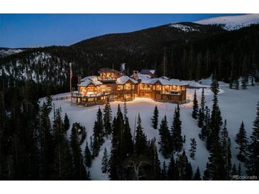 Stunning mountain estate features a log cabin design and beautiful landscaping surrounded by snow-covered trees at 300 Little Sallie Barber Trl, Breckenridge, CO 80424