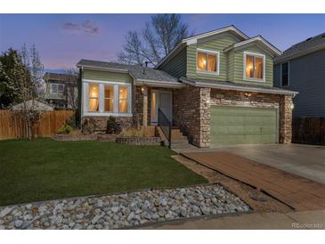 Charming two-story home featuring a stone facade, green siding, well-maintained lawn, and a two-car garage at 13199 Ash St, Thornton, CO 80241