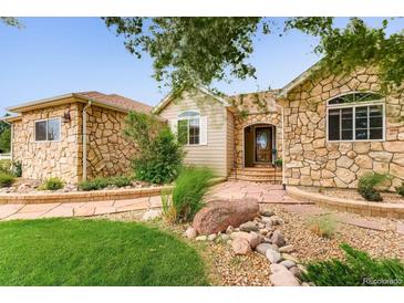 Stone exterior home with landscaping and a paved walkway leading to the entrance at 15540 Ulster St, Thornton, CO 80602