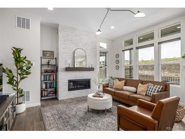 Bright living room boasts modern fireplace with white brick, hardwood floors, and ample natural light at 11027 Sunshimmer Cir, Parker, CO 80134