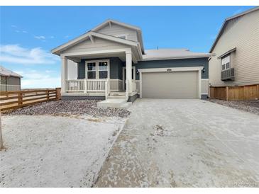 Charming single-Gathering home with a two-car garage, covered porch and wintry landscape at 12892 E 99Th Pl, Commerce City, CO 80022