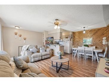 Open-concept living area featuring a wood accent wall, wood flooring, and a comfortable seating arrangement at 1272 S Uvalda St, Aurora, CO 80012