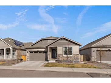 Charming single-story home featuring a stone facade, well-kept lawn, and attached two-car garage at 8390 S Cody Way, Littleton, CO 80128