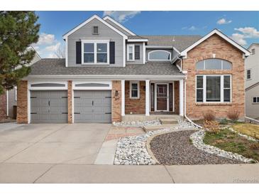 Charming two-story home featuring a brick facade, gray siding, attached garages, and manicured front yard at 787 Huntington Pl, Highlands Ranch, CO 80126