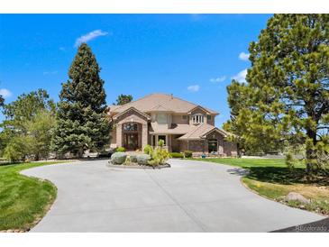 Elegant two-story home boasts a circular driveway, lush landscaping, and a welcoming entrance at 7645 Fox Creek Trl, Franktown, CO 80116