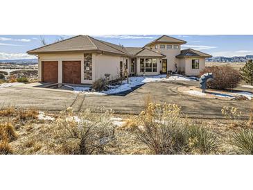 Inviting stucco home with two-car garage and circular driveway situated in scenic snowy landscape at 8611 Coachlight Way, Littleton, CO 80125