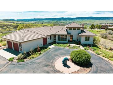 Elegant home boasts a circular driveway, tile roof, and stunning mountain views, perfect for luxurious living at 8611 Coachlight Way, Littleton, CO 80125