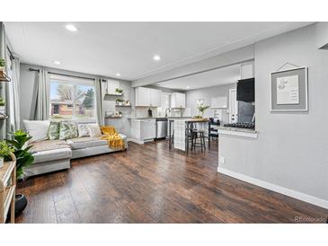Open concept living room and kitchen with hardwood floors, a comfortable couch, and plenty of natural light at 1010 S Osceola St, Denver, CO 80219