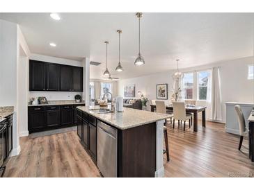 Open kitchen featuring a granite island, stainless steel appliances, dark cabinetry and hardwood floors at 9080 Fig St, Arvada, CO 80005