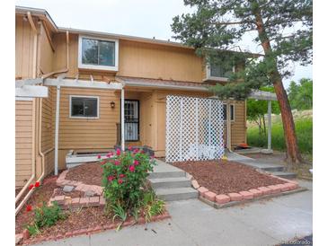 Tan two-story townhouse exterior with landscaping and a white lattice at 9105 Oberon Rd # 2, Arvada, CO 80004