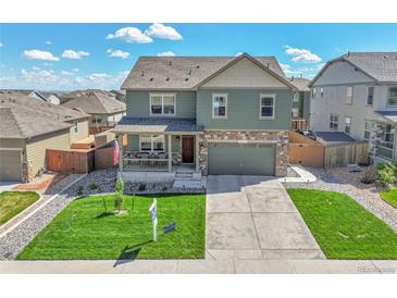 Inviting home with a covered front porch, green lawn, and an attached two-car garage at 7888 E 139Th Pl, Brighton, CO 80602
