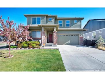 Charming two-story home with a well-manicured lawn, a driveway, and a beautiful flowering tree in the front yard at 26909 E Cedar Ave, Aurora, CO 80018