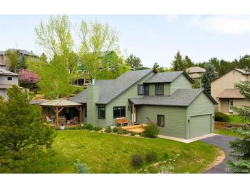 Beautiful exterior of home with green siding, covered porch, manicured lawn and attached garage at 3257 Sun Ridge Ln, Evergreen, CO 80439
