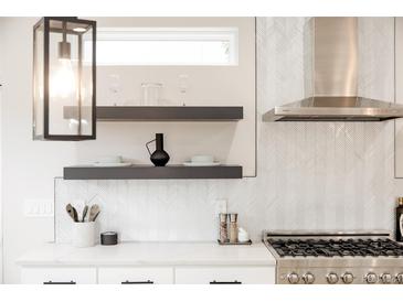 Modern kitchen featuring quartz countertops, floating shelves, and stainless steel range hood at 2040 W 45Th Ave, Denver, CO 80211