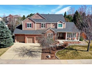 Charming two-story home featuring a three-car garage, brick accents, and covered front porch perfect for relaxing at 580 Crossing Cir, Castle Pines, CO 80108