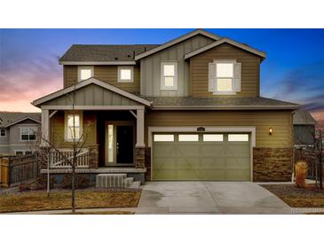 Charming two-story home featuring a two-car garage and a welcoming front porch, stone veneer, neutral color and meticulous landscaping at 5686 Eagle River Pl, Brighton, CO 80601