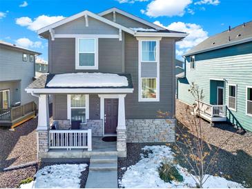 Charming two-story home showcasing a covered porch, stone accents, and a well-maintained front yard, creating an inviting curb appeal at 470 Kiowa Ave, Bennett, CO 80102