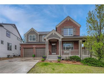 Charming two-story brick home with a covered front porch and a well-manicured lawn at 3434 Fantasy Pl, Castle Rock, CO 80109