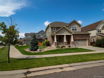 Charming two-story home featuring a brick facade and a welcoming front porch with classic columns at 5626 S Biloxi Way, Aurora, CO 80016