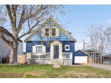Charming blue two-story home with a front porch, garage, and beautifully landscaped front yard at 5103 Quitman St, Denver, CO 80212