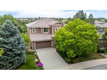 Charming two-story home with a well-manicured lawn, mature trees, and a spacious driveway leading to an attached two-car garage at 3126 Aspen Creek Dr, Highlands Ranch, CO 80129