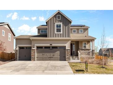 Charming two-story home with a three-car garage, stone accents, and covered porch at 24325 E Ada Pl, Aurora, CO 80018