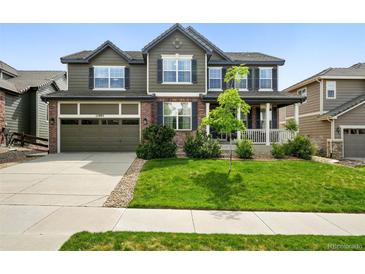 Traditional two-story home with a two-car garage, inviting curb appeal, and lush green lawn at 11985 Singing Winds St, Parker, CO 80138