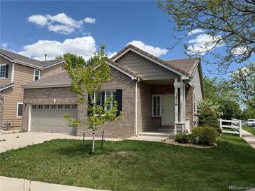 Charming brick home featuring a well-manicured lawn, mature tree, and an attached two-car garage at 1216 S Flat Rock Cir, Aurora, CO 80018