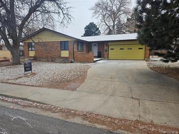 Charming single-story home with a brick facade, yellow trim, and an attached garage, nestled in a serene neighborhood at 2907 S Upham St, Denver, CO 80227