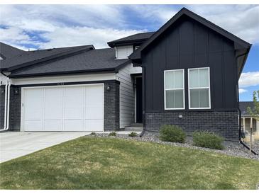 Modern home showcasing black and white exteriors, a white garage door, and manicured lawn at 8244 S Queen St, Littleton, CO 80127