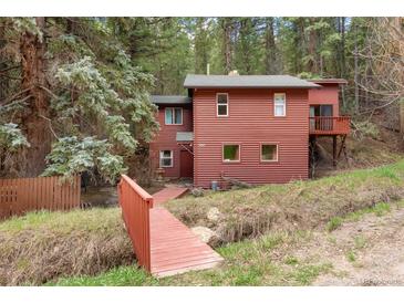 Charming cabin-style home featuring a red-toned exterior and surrounded by lush greenery and mature trees at 17422 N Canyon Rd, Littleton, CO 80127