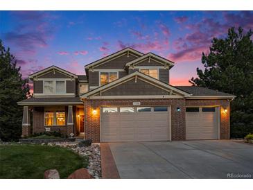 Beautiful two-story home with a three-car garage and brick accents, illuminated by warm exterior lighting at 7624 Russell Ct, Arvada, CO 80007