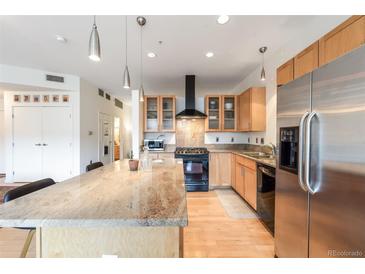 Bright kitchen features stainless steel appliances, an island with granite countertops, and wooden cabinets at 1438 Little Raven St # 301, Denver, CO 80202