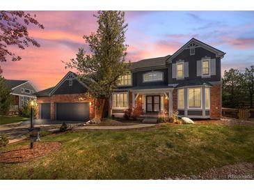 Elegant two-story home with brick and siding exterior, mature landscaping, and an attached three-car garage at 404 Yarrow Pl, Castle Pines, CO 80108