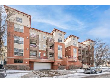 Modern brick apartment building with balconies, an attached garage, and well-kept landscaping, all under a clear blue sky at 1767 N Pearl St # 308, Denver, CO 80203