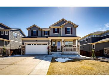 Charming two-story home with a welcoming front porch, well-manicured lawn, and two-car garage at 7150 E 121St Pl, Thornton, CO 80602