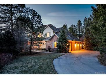 Two-story home featuring brick and siding exterior, attached garage, mature trees, and a curved driveway at 870 Homestake Ct, Castle Rock, CO 80108