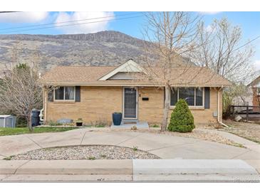 Charming brick home featuring a well-maintained front yard, a mountain in the background, and mature trees at 217 Ford St, Golden, CO 80403
