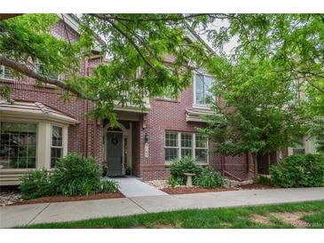Inviting two-story red brick home featuring lush landscaping and a welcoming front entrance at 9165 Kornbrust Dr, Lone Tree, CO 80124