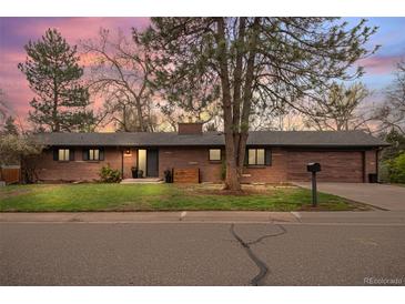 Charming brick ranch-style home featuring a well-maintained front yard and attractive landscaping at dusk at 8750 W 8Th Ave, Lakewood, CO 80215
