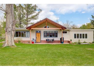 Charming home featuring a wooden porch, lush green lawn, and beautiful natural light at 9445 Lykins Pl, Longmont, CO 80503