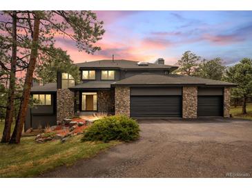 Striking two-story home with a three-car garage and stone accents at dusk at 1423 Belford Ct, Evergreen, CO 80439