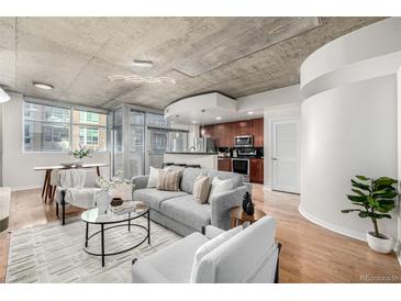 Cozy living room with modern decor, concrete ceiling, hardwood floors, and an open layout to the kitchen at 1700 Bassett St # 406, Denver, CO 80202
