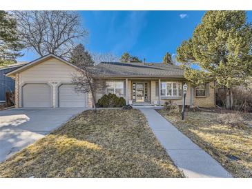 Charming ranch-style home with a well-manicured lawn and two-car garage under a clear blue sky at 5749 S Lansing Way, Englewood, CO 80111