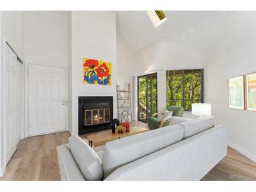 Bright living room features a cozy fireplace, skylight, and slider to balcony at 4850 E Kentucky Ave # C, Denver, CO 80246