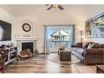 Spacious living room with hardwood floors, fireplace, and sliding glass doors to private balcony at 23406 E 5Th Pl # 203, Aurora, CO 80018