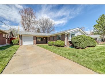 Charming brick ranch home with a well-manicured front yard and a long driveway to an attached garage at 1669 S Kearney St, Denver, CO 80224