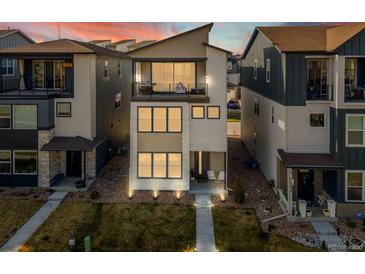 Modern two-story home with stone accents, a balcony, manicured lawn, and beautiful landscaping at 12242 W 56Th Pl, Arvada, CO 80002