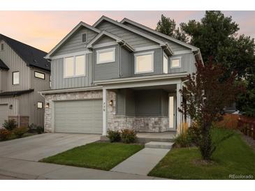 Charming two-story home showcasing gray siding, stone accents, a well-maintained lawn, and an attached two-car garage at 779 Kohlor Dr, Lafayette, CO 80026