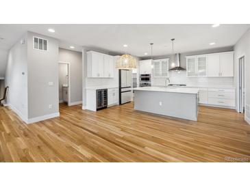 Bright, open kitchen featuring white cabinets, stainless steel appliances, an island, and wooden floors at 779 Kohlor Dr, Lafayette, CO 80026